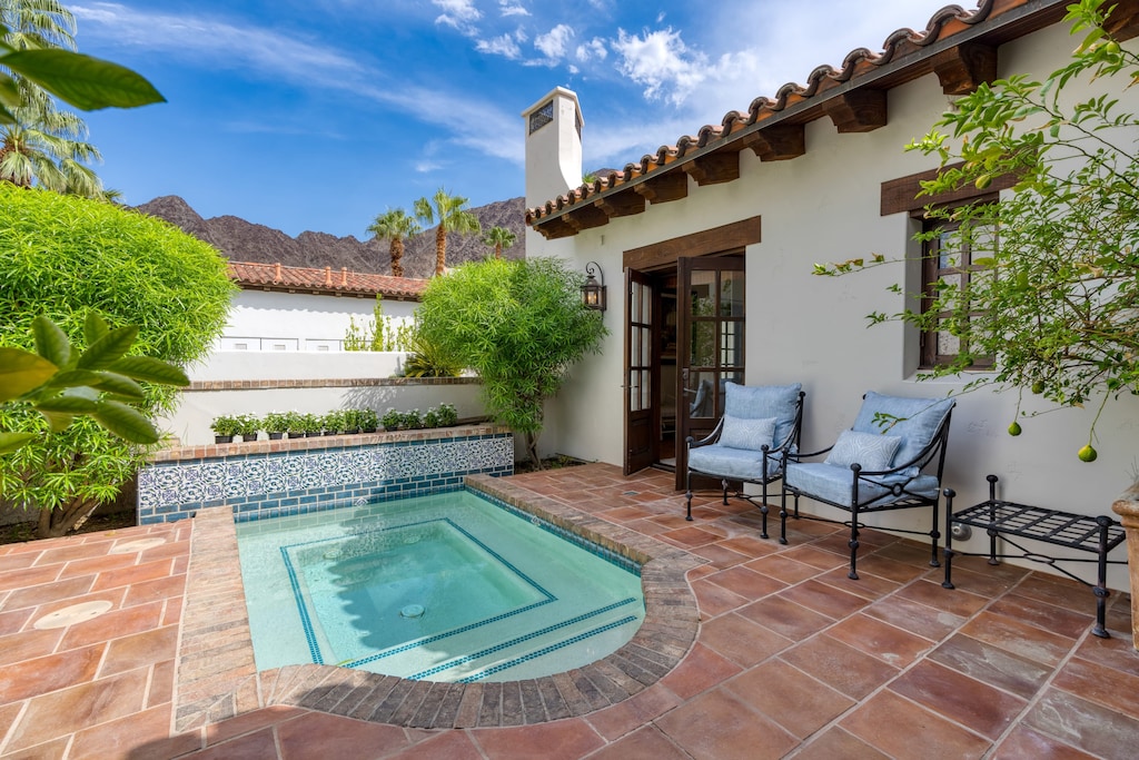 Serene patio area featuring a small, tiled plunge pool and two comfortable chairs, perfect for relaxing on a sunny day.