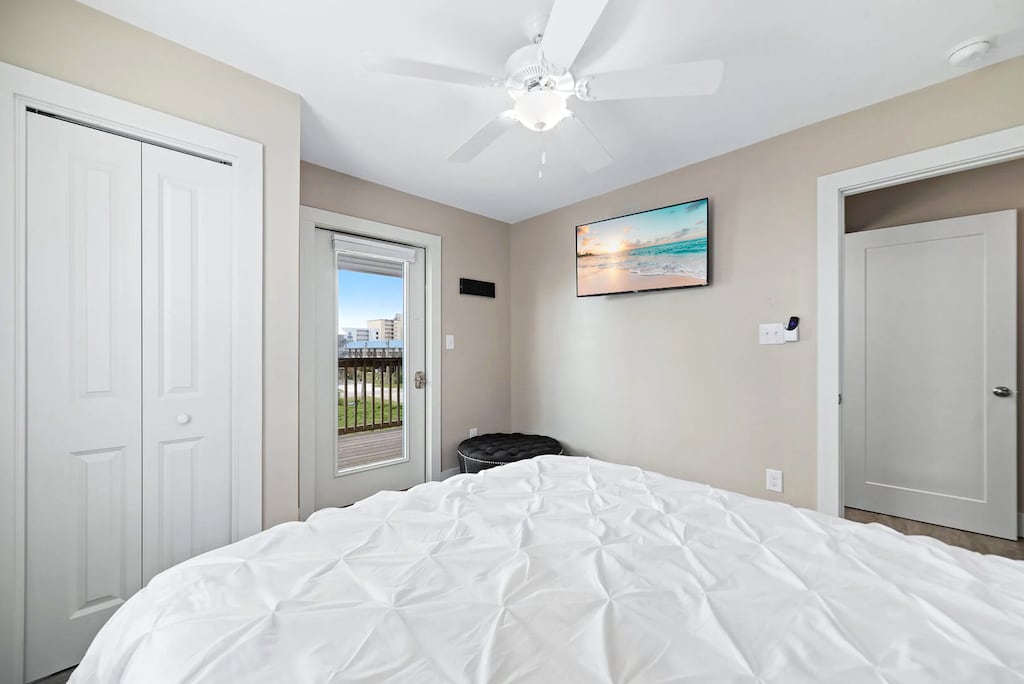 Guest bedroom featuring a cozy queen bed, a ceiling fan, and a TV with a view of the outdoor deck