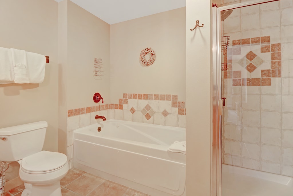 Elegant bathroom featuring a relaxing soaking tub with decorative tile accents and a glass-enclosed walk-in shower. Ideal for unwinding after a day on the slopes.
