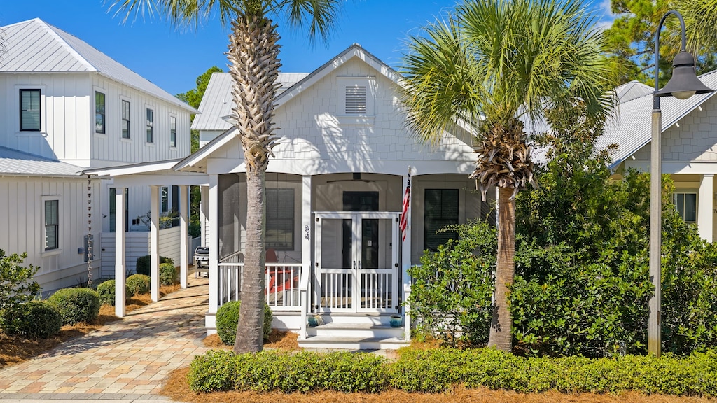 Charming coastal cottage with a screened porch and palm-lined entryway.