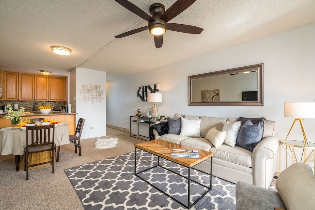 Experience open-plan living with a cozy sofa, dining area, and a fully equipped kitchen.