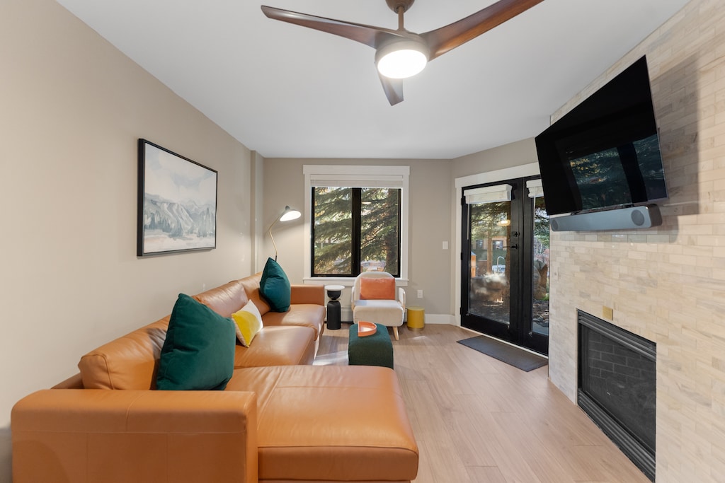 Living area featuring a gas fireplace, queen sleeper sofa, mounted TV, and access to the private patio. 