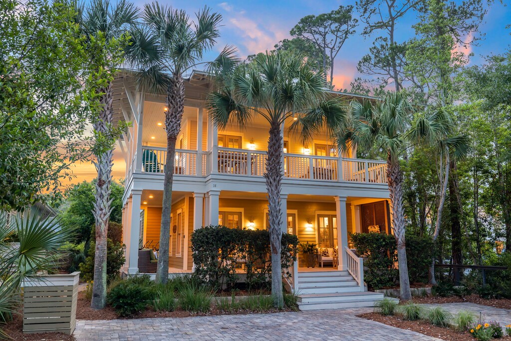 A coastal retreat nestled among palms and pines, glowing warmly as twilight settles over the property—a perfect arrival scene for your getaway.