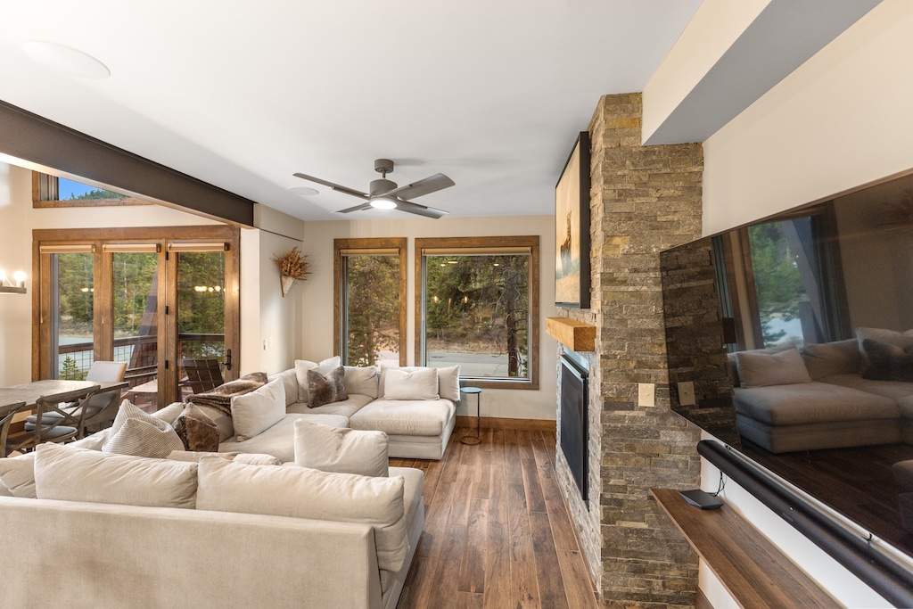 The open concept living space features ample seating surrounding a cozy fireplace and TV, plus access to the private balcony. 