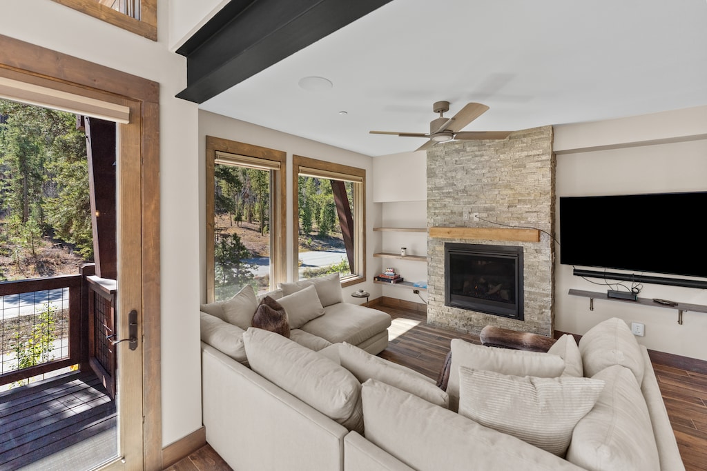 The open concept living space features ample seating surrounding a cozy fireplace and TV, plus access to the private balcony. 