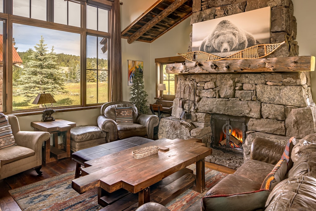 Curl up by the crackling stone fireplace in this inviting living room, where rustic charm meets mountain elegance. Sink into plush leather seating and let your worries melt away as natural light floods in through soaring windows.