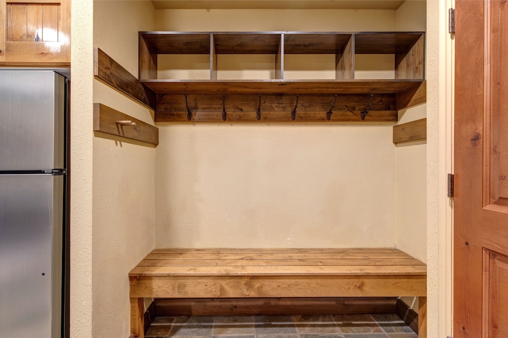 Your own organized mudroom awaits with custom wooden storage cubbies and hooks for your gear, plus a sturdy bench to sit while you lace up for mountain adventures.