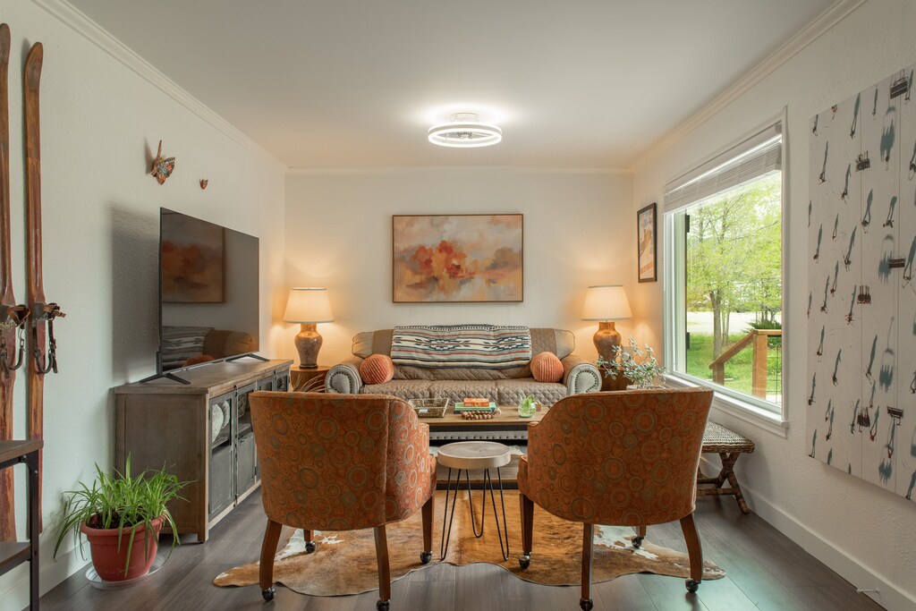 A cozy and well appointed Living room with large window, Smart TV and comfortable clean furnishings