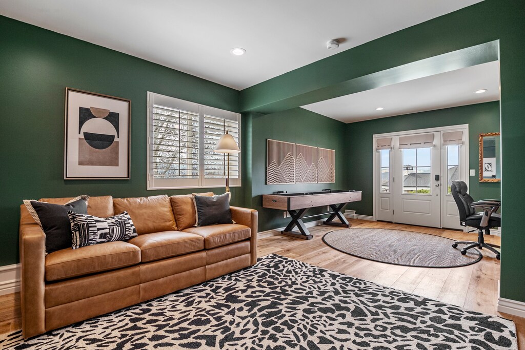 A large media room with desk, smart TV, shuffle board and sleeper sofa