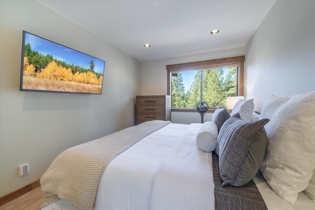 Serene retreat: The primary bedroom features a spacious king bed, a flat-screen TV for unwinding, and a large window that frames the breathtaking views of the Tahoe forest.