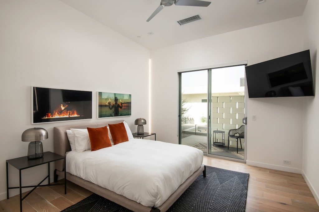 A bright queen bedroom offering modern design, a smart TV, and direct access to a private, enclosed patio.