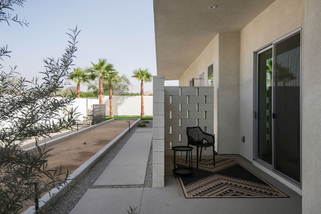 A view of the private side yard, featuring a shaded patio seating area and the home's bocce ball court.