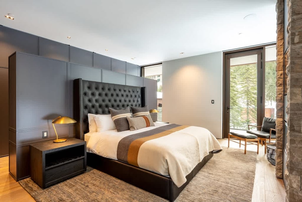 - Elegant bedroom with plush bedding and mountain views  
- Warm tones and cozy lighting create a restful atmosphere  
- Direct access to nature through large glass doors  
