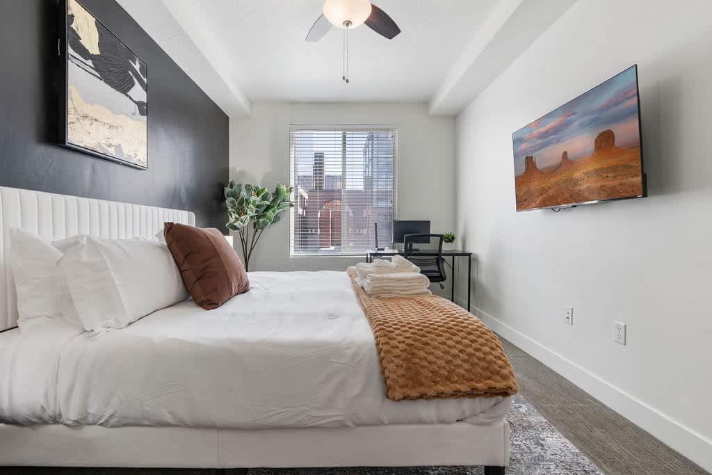 Relax and recharge in this elegant bedroom, featuring a king bed, TV, scenic window, and a touch of greenery.