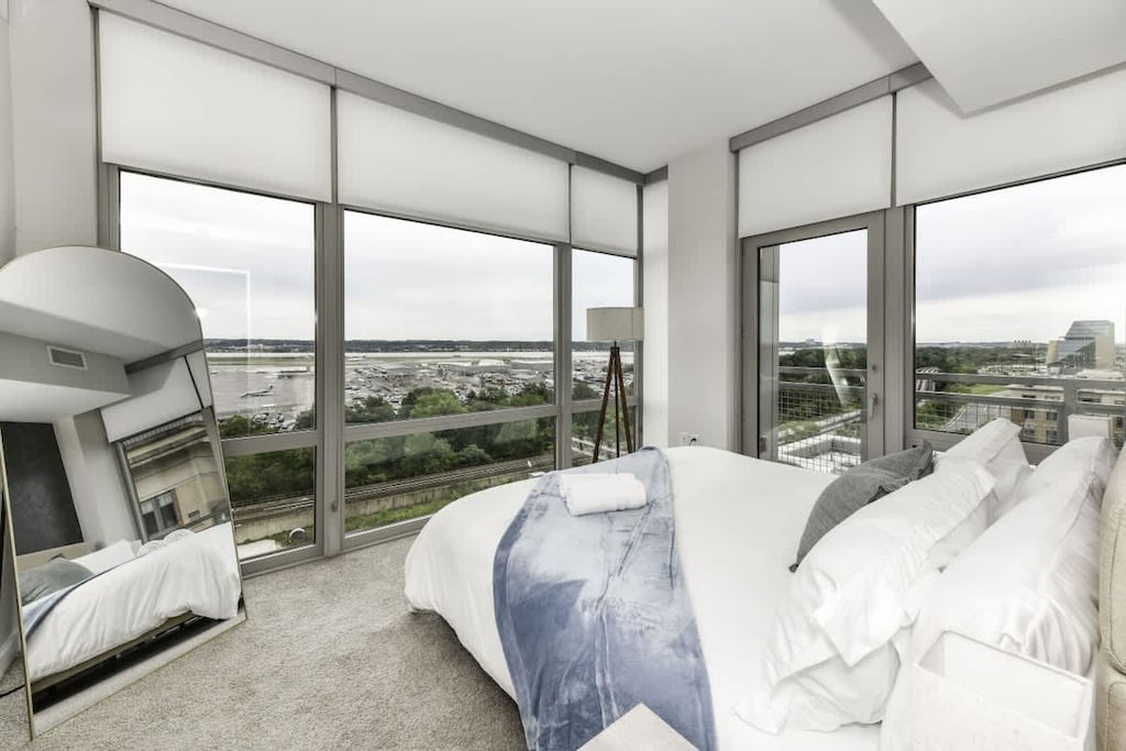 Runway Views ✈️ Relax in a modern king bedroom with floor-to-ceiling windows to watch planes land & take off right from your bed!