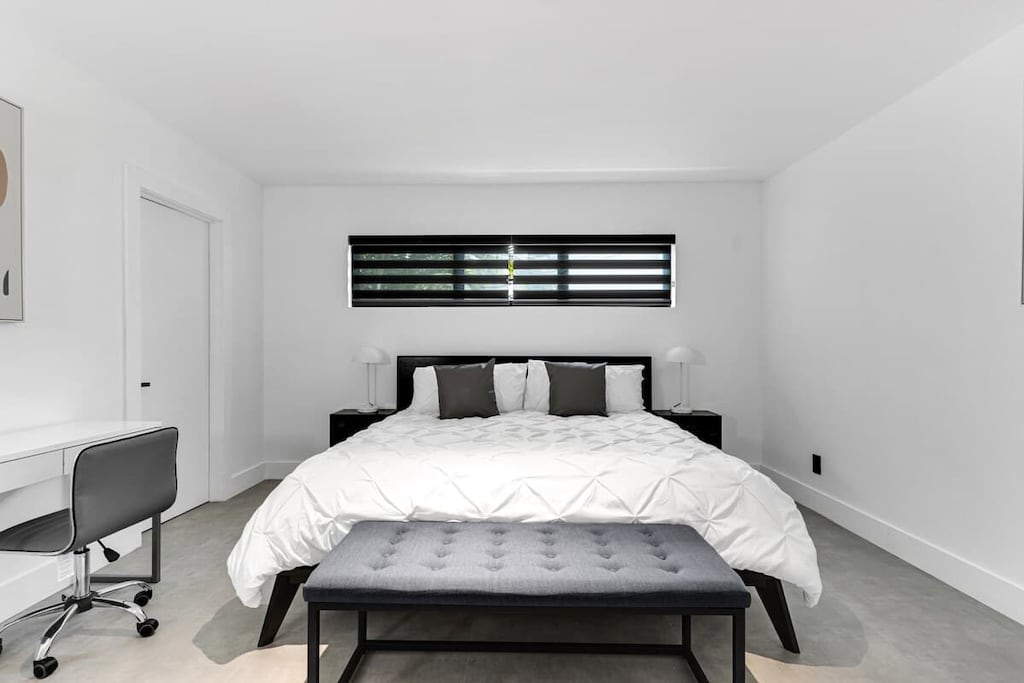 "Sleep soundly in this serene, modern bedroom with cozy bedding, sleek design, and a dedicated workspace—perfect for couples, solo travelers, or remote workers booking a stylish vacation rental."