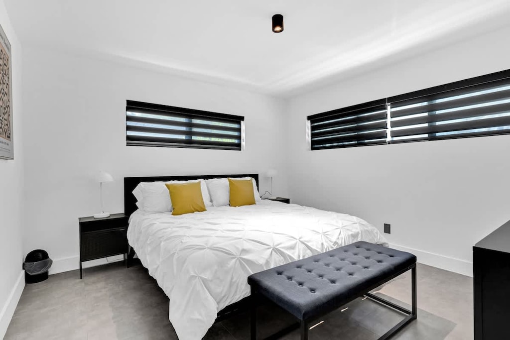 "Enjoy restful nights in this modern, minimalist bedroom with cozy bedding, stylish accents, and natural light—perfect for couples, solo travelers, or remote workers booking a vacation rental."