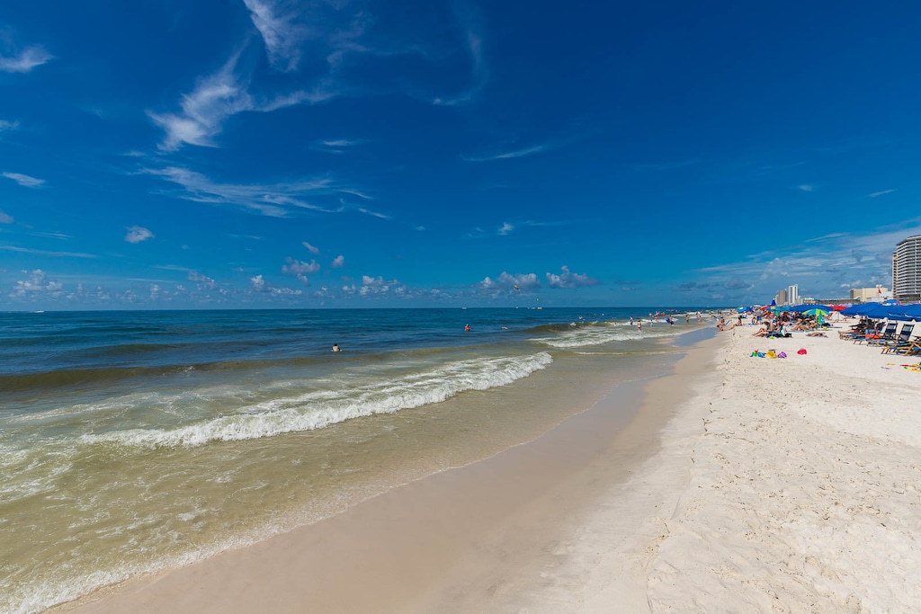 Experience the beautiful beachfront with soft sand, gentle waves, and vibrant beachgoers for a perfect day by the water