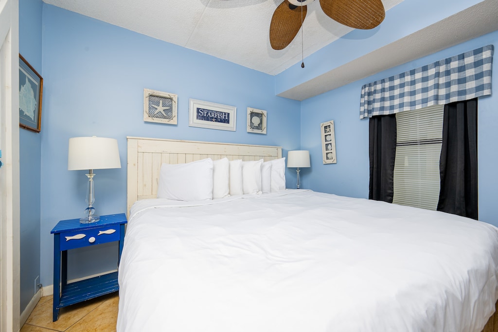 This inviting bedroom features a comfortable bed, cheerful blue walls, and charming coastal decor for a relaxing stay