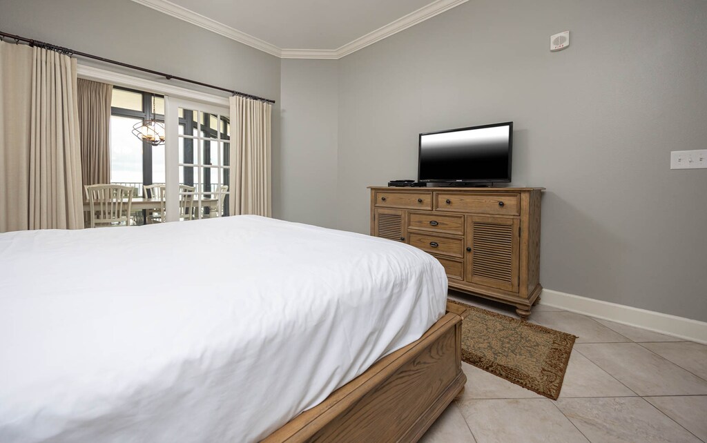 The master bedroom features a cozy atmosphere with king, a TV and a lovely view of the dining area through large windows