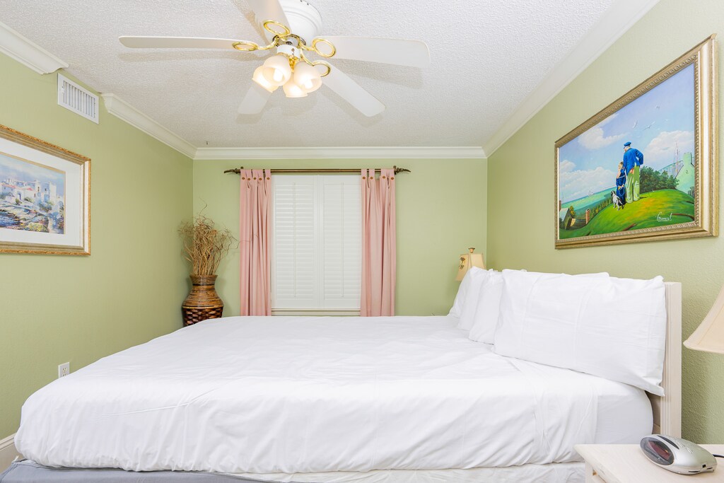 Relax in this tranquil guest bedroom featuring a queen bed, soft green walls, and charming art, perfect for a restful getaway