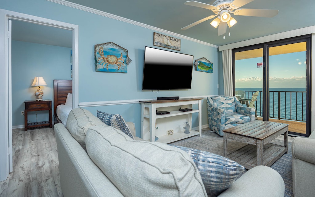 This inviting living area features a large TV, queen sofa-sleeper, coastal decor, and a beautiful view from the balcony
