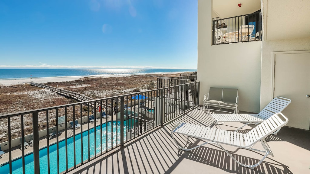 Pool area and beach, featuring lounge chairs and a clear view of the sparkling gulf waters