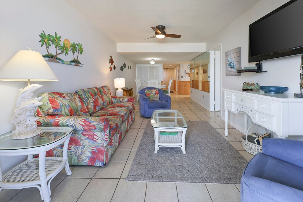 Living area features tropical decor, comfortable seating, and a large flat-screen TV for relaxation