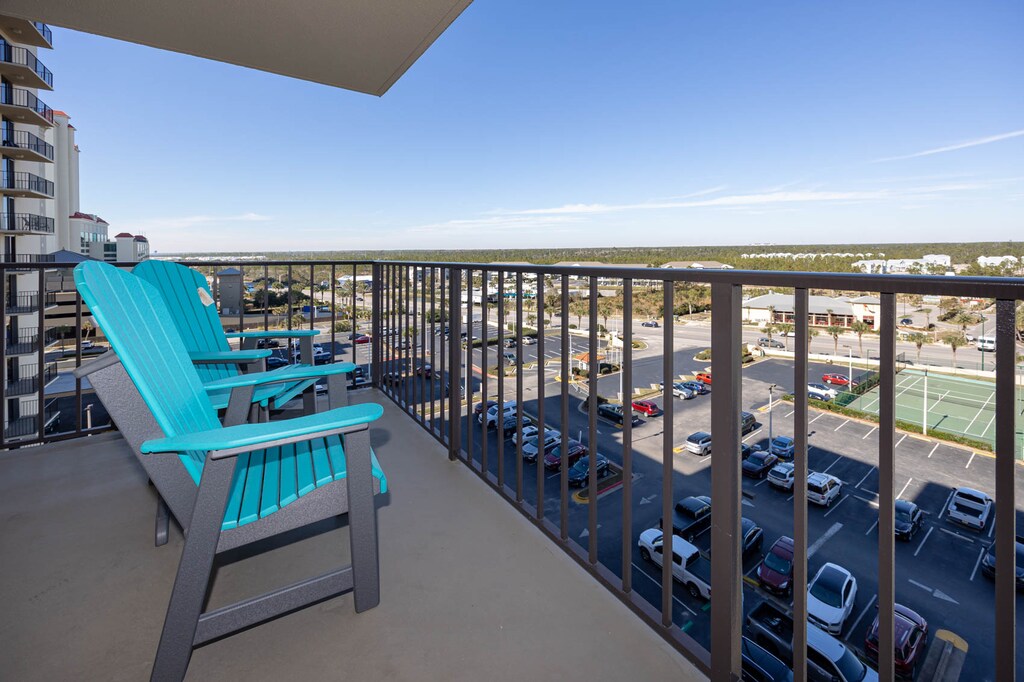 Relax in vibrant turquoise chairs on the balcony, enjoying expansive views of the surrounding area and nearby tennis courts