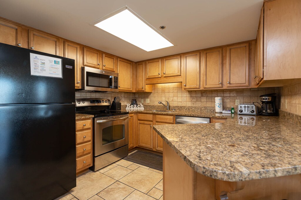 This fully-equipped kitchen features warm wood cabinetry, granite countertops, and a convenient breakfast bar