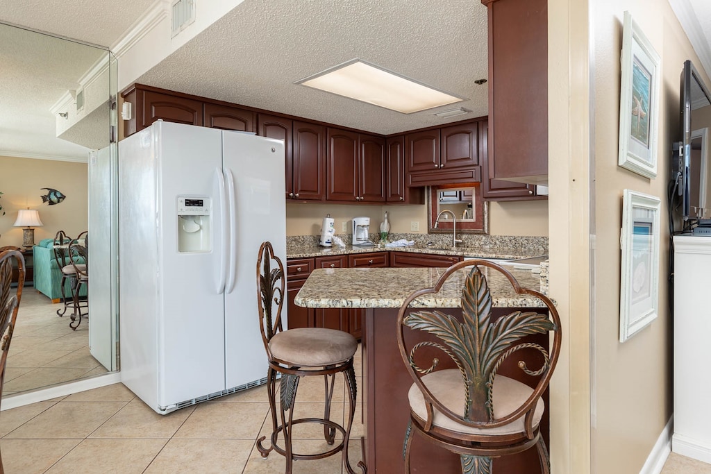 The well-appointed kitchen features rich wood cabinetry, a granite breakfast bar with stylish seating, and modern appliances