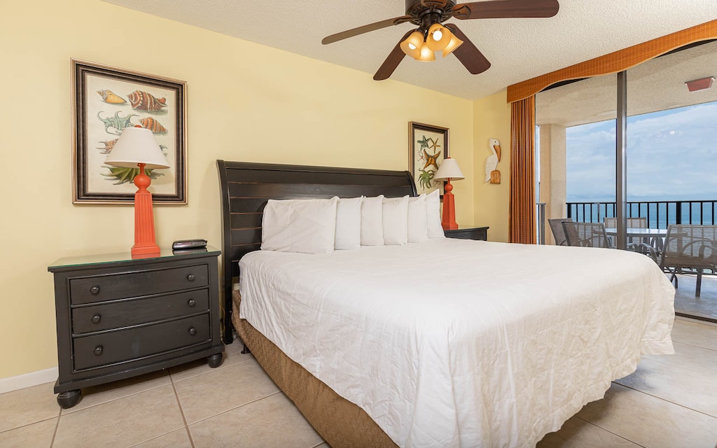 The inviting master bedroom features a plush king bed, vibrant orange lamp, and a balcony with a beach view