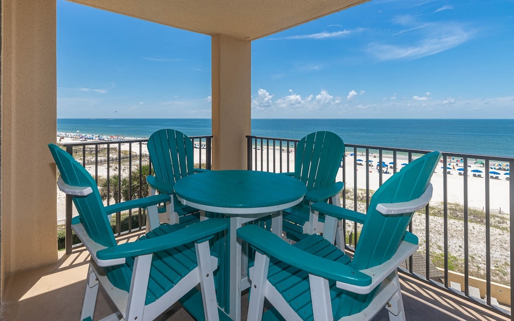 A turquoise outdoor table set invites relaxation on the balcony, offering a direct view of the beach and tranquil waters