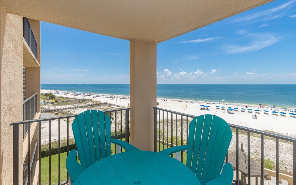 A vibrant turquoise table with matching chairs offers a perfect spot to enjoy stunning views of the beach and azure waters