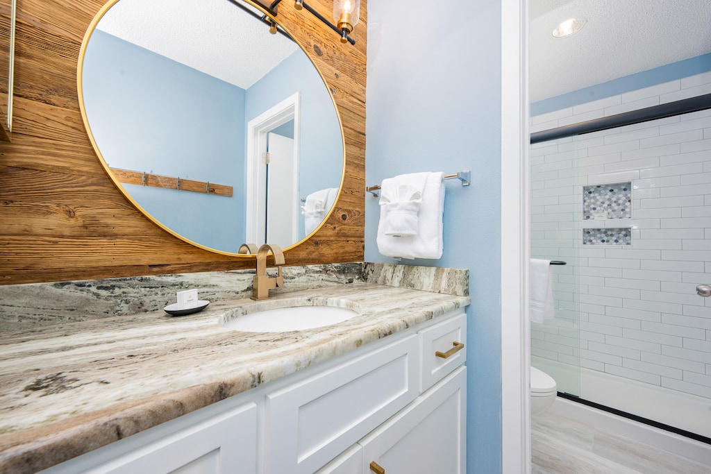 The master bath features a stylish round mirror, elegant countertop, and a walk-in shower with modern tile accents