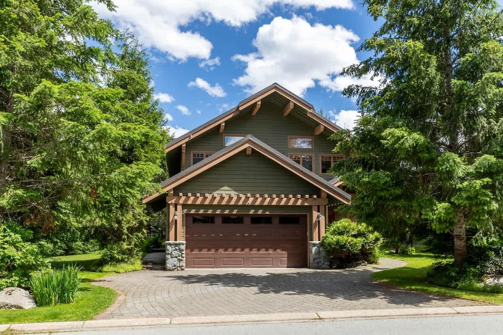 - Green chalet with double garage framed by forested mountain views  
- Driveway leads to a cozy home perfect for year-round getaways  
- Mountain charm meets comfort in this scenic woodland retreat  