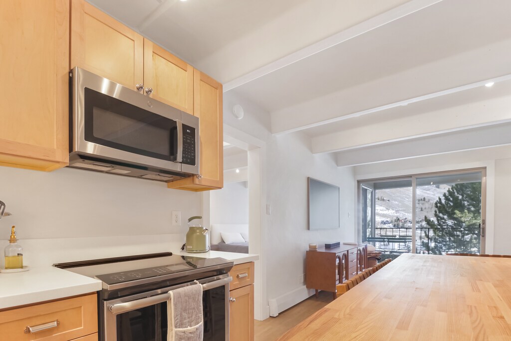 Your fully equipped kitchen features modern appliances and stunning mountain views from the dining area's large windows.