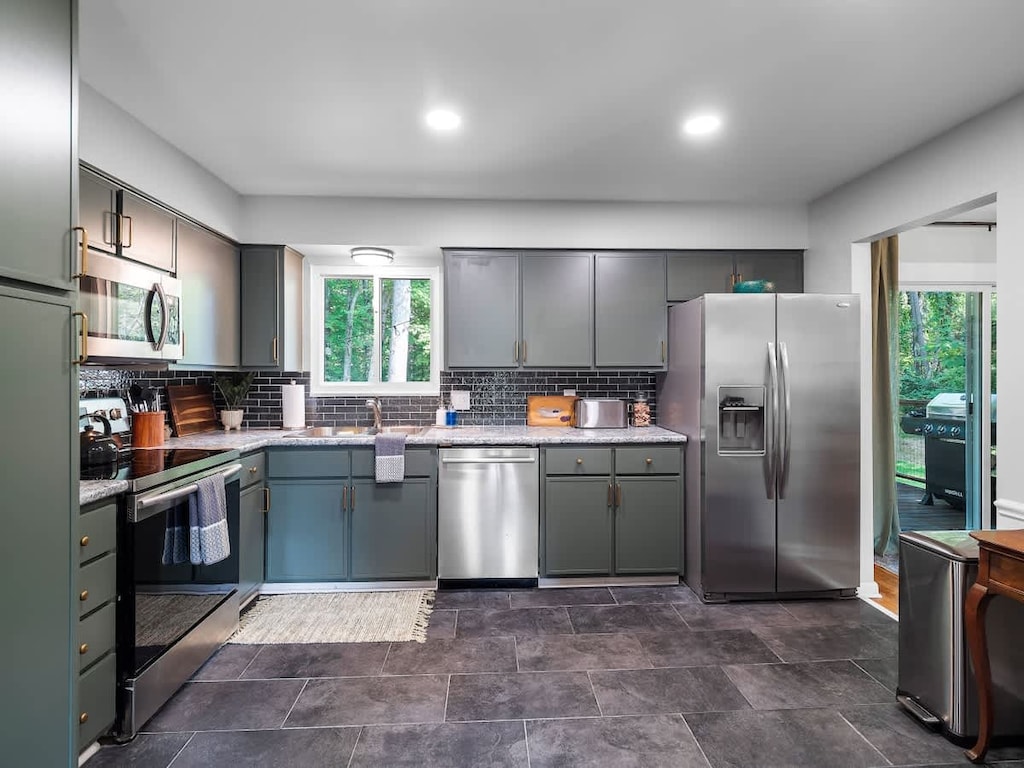 Fully equipped modern kitchen featuring sleek grey cabinets, stainless steel appliances, and a walk-out to the patio. 🍽️🌳