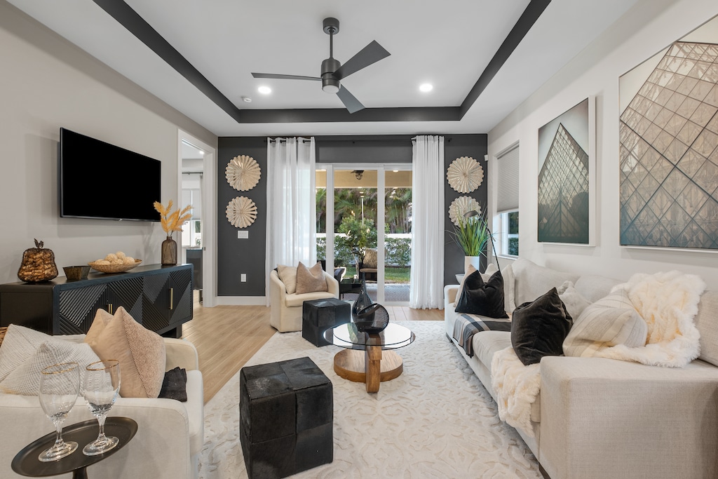 Sink into plush white sofas in your sophisticated living room, where modern design meets comfort beneath elegant tray ceilings and natural light.