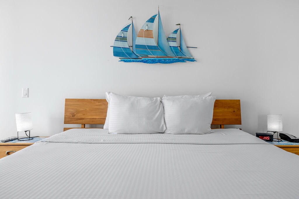 Drift off to sleep in your coastal-themed bedroom, where crisp white linens and charming sailboat art create a peaceful nautical retreat.