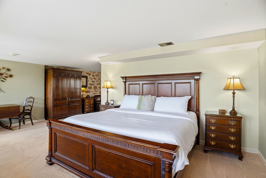 Sink into plush bedding and elegant wood furnishings where classic charm meets your comfort in this spacious, peaceful bedroom retreat.