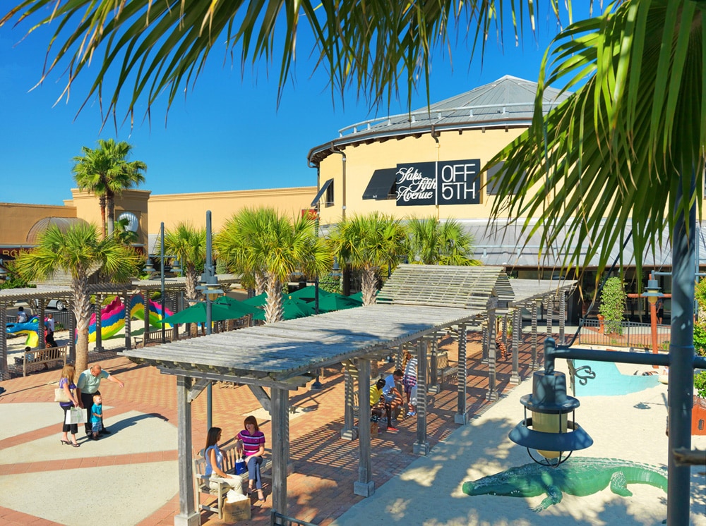 Tropical aqua park with water slides, play areas, and palm trees under sunny skies.