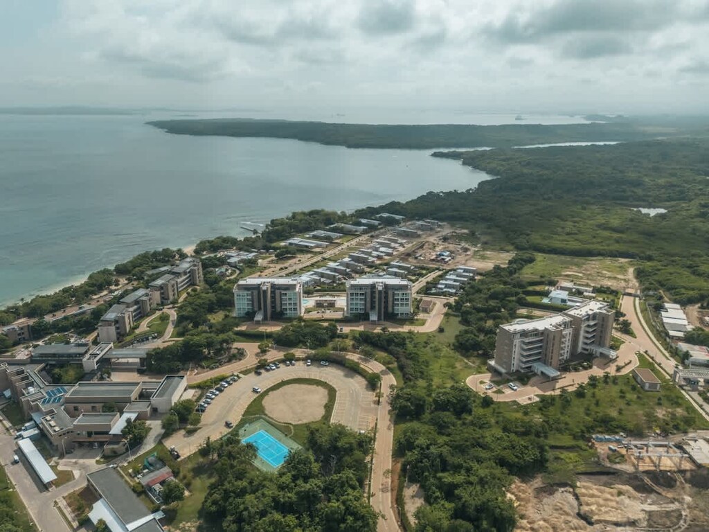 - Aerial view of beachfront community with lush greenery  
- Scenic coastline and modern buildings beside the ocean  
- Peaceful coastal setting showcasing nature and amenities  
