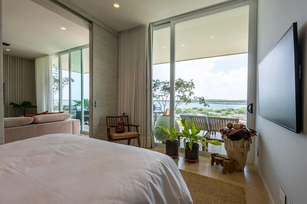 - Bedroom with wide balcony views and natural accents  
- Cozy decor with plants and wooden chair details  
- Soft bedding and serene lighting create a warm escape  