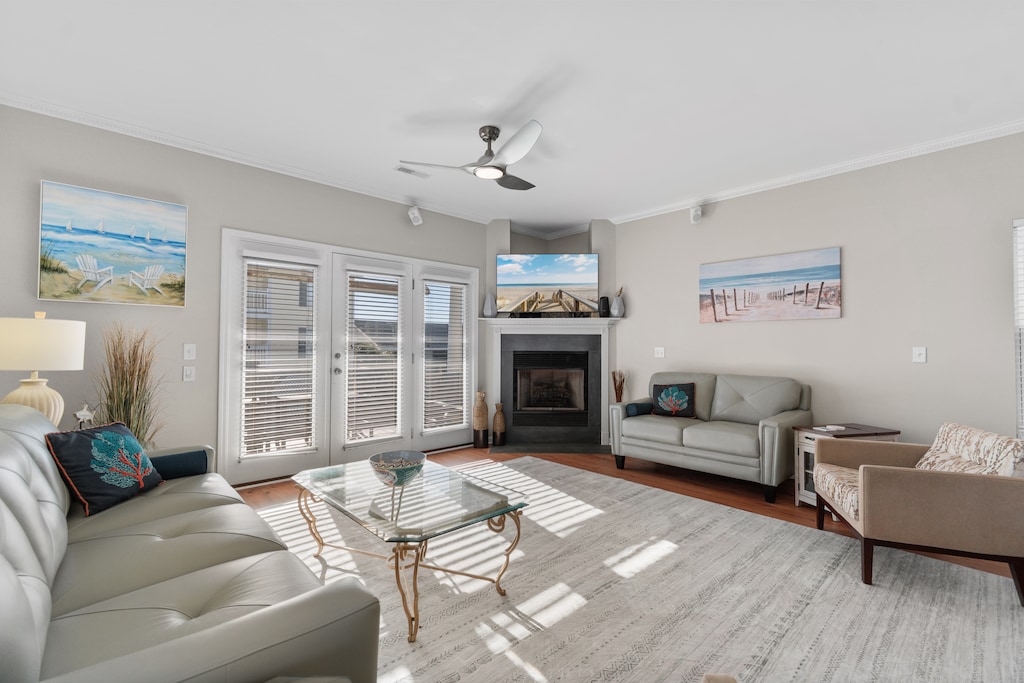 Relax in your bright living room with coastal artwork, cozy fireplace, and French doors opening to natural light.