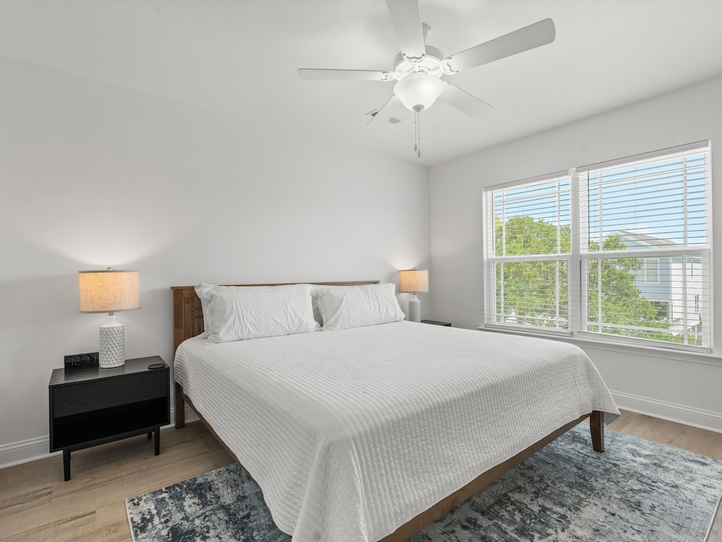 Rest peacefully in your bright bedroom with soft linens, warm bedside lighting, and gentle breezes from the ceiling fan overhead.