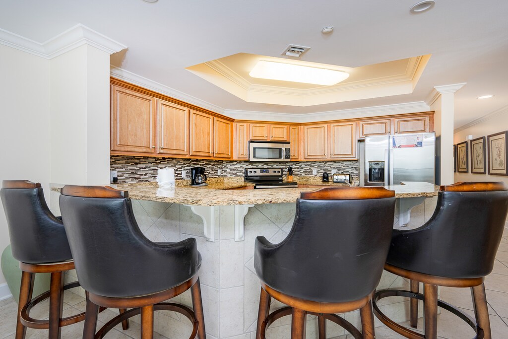 Kitchen featuring granite countertops, stainless appliances, and stylish bar seating for a cozy dining experience