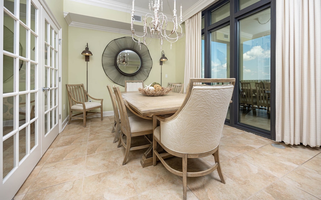 This dining area features a stylish wooden table with elegant chairs, a chandelier, and large windows offering a serene view