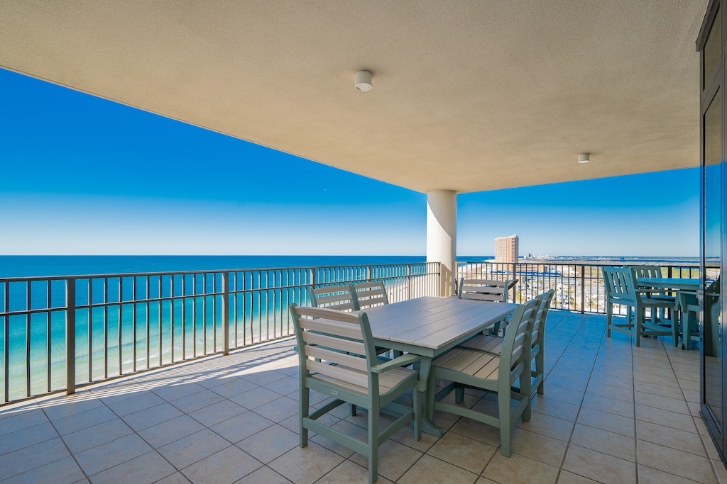 This expansive balcony features a dining table with panoramic beach views, perfect for enjoying meals in the sun