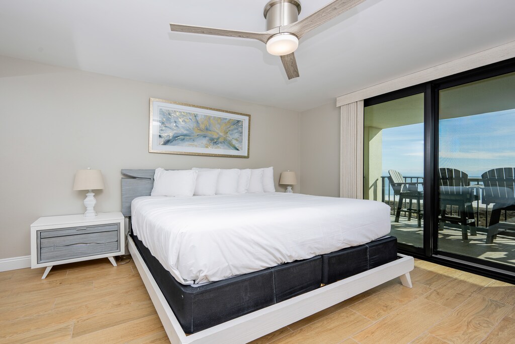 Master suite bedroom featuring a king bed, modern ceiling fan, and access to the balcony on the beach